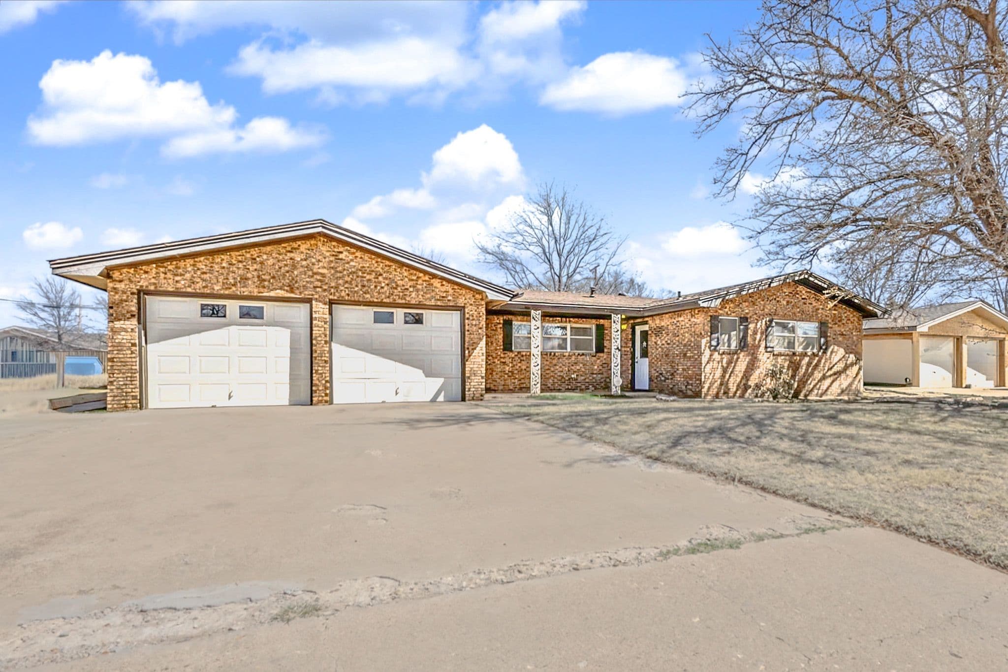 Single-story brick ranch home exterior in Levelland, TX with attached garage, photographed in hand-blended HDR.