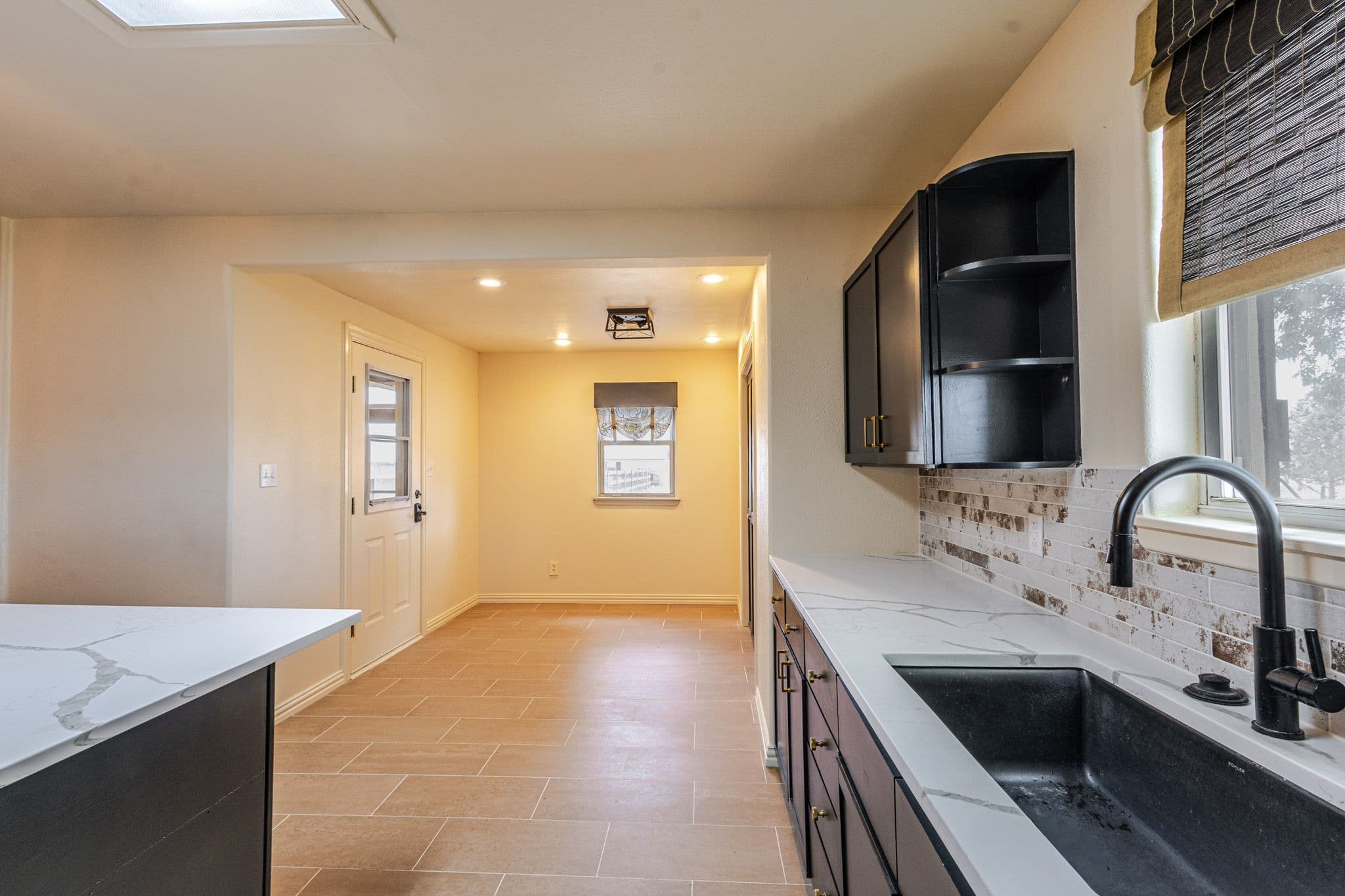 Interior shot of kitchen sink and countertop with dining room in background
